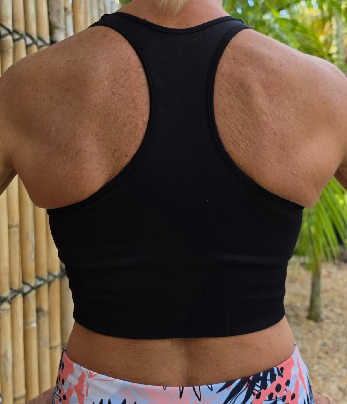 Black racerback sports bra with a snug supportive fit shown from the back as part of the relaxed crop top collection