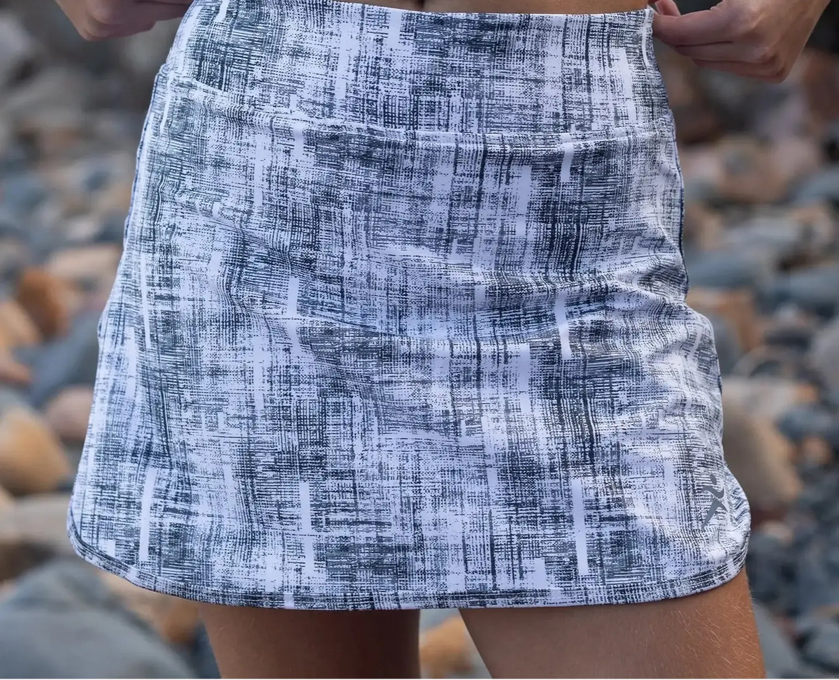 A stylish white and navy blue abstract patterned high-waisted skort with pockets ideal for tennis and athletic wear
