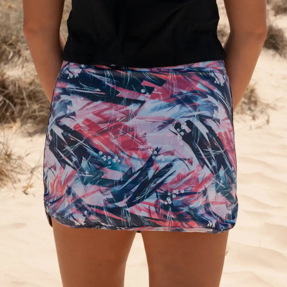 Skort with an abstract print design in vibrant pink, white, and navy blue, including practical pockets on the undershorts