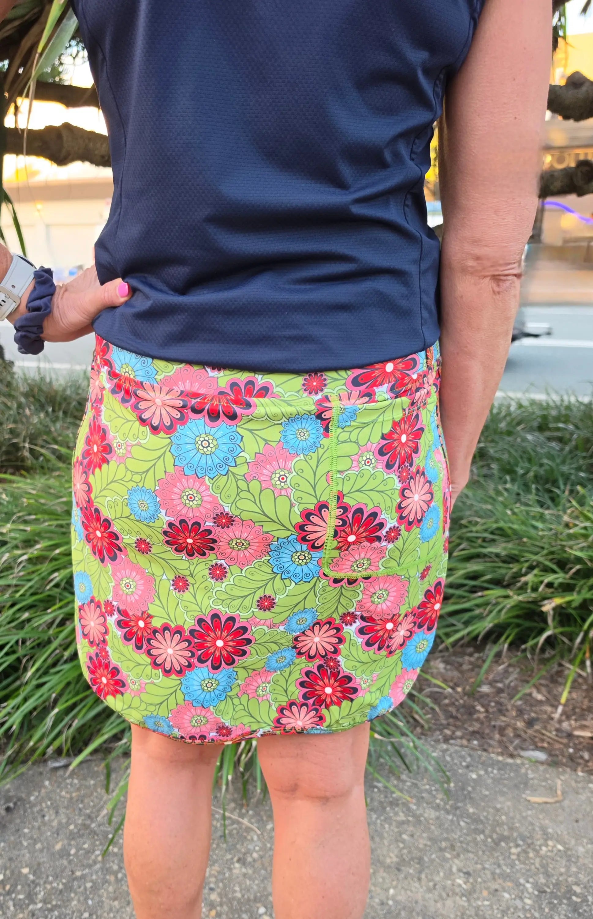 Cara longer skort with pockets in vibrant green featuring bold pink red and blue floral pattern and mini skirt style