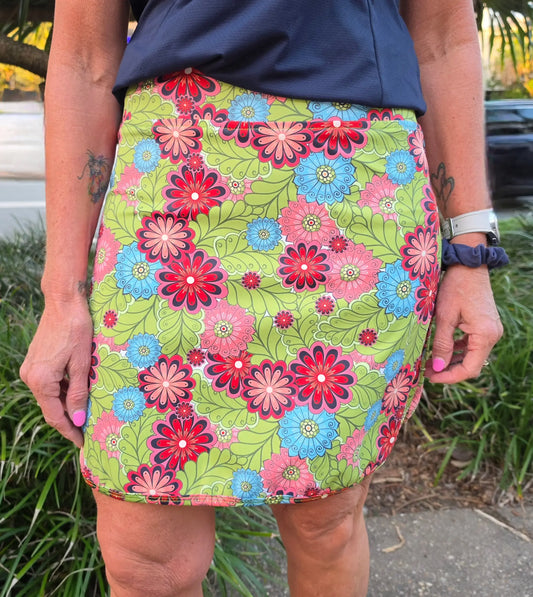 Cara Longer Skort with pockets is a lime green floral mini skirt with bold red and blue flowers outlined in black