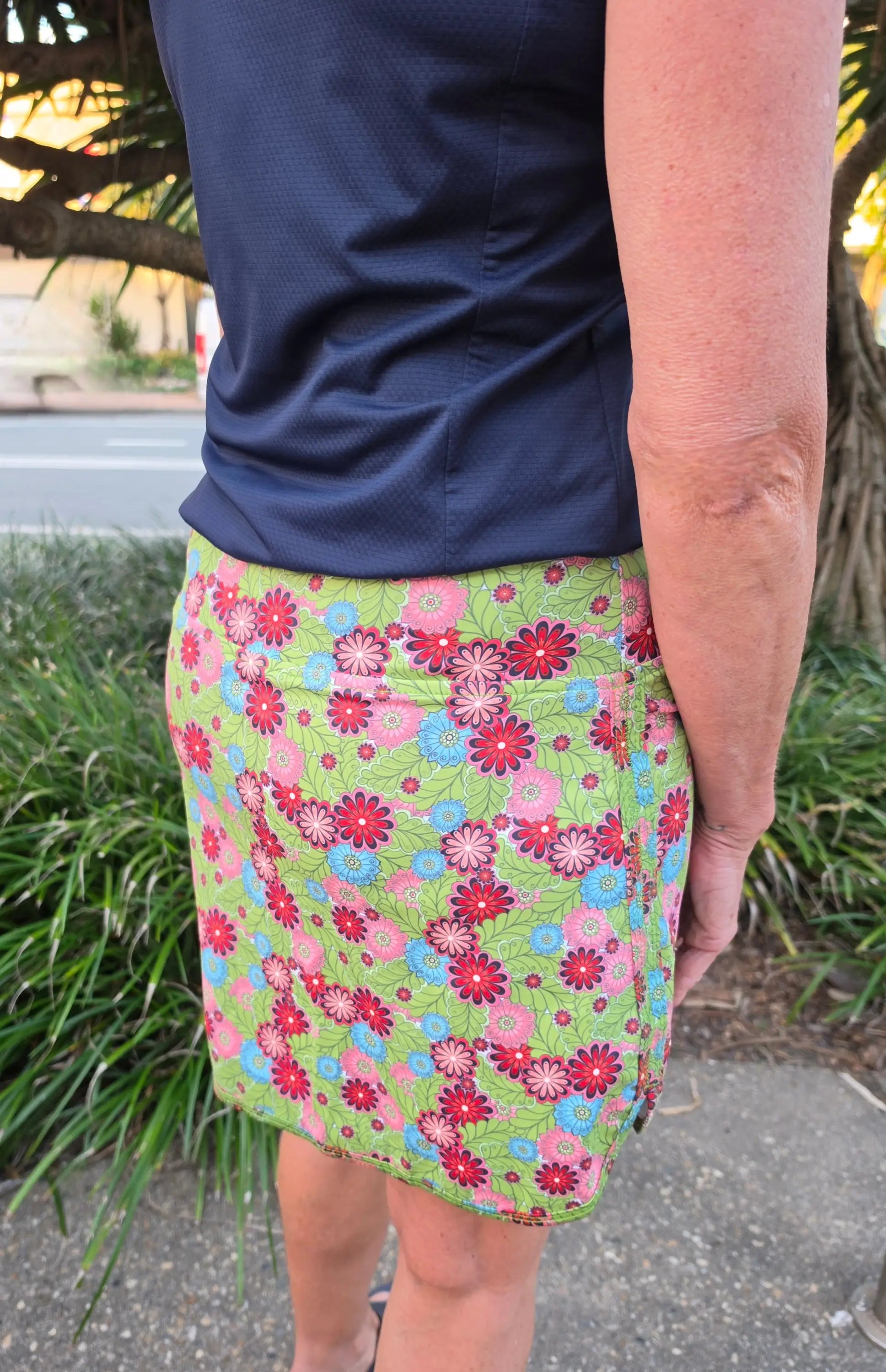 Cate skort with pockets featuring a vibrant green floral pattern with pink red and blue flowers and leaf accents