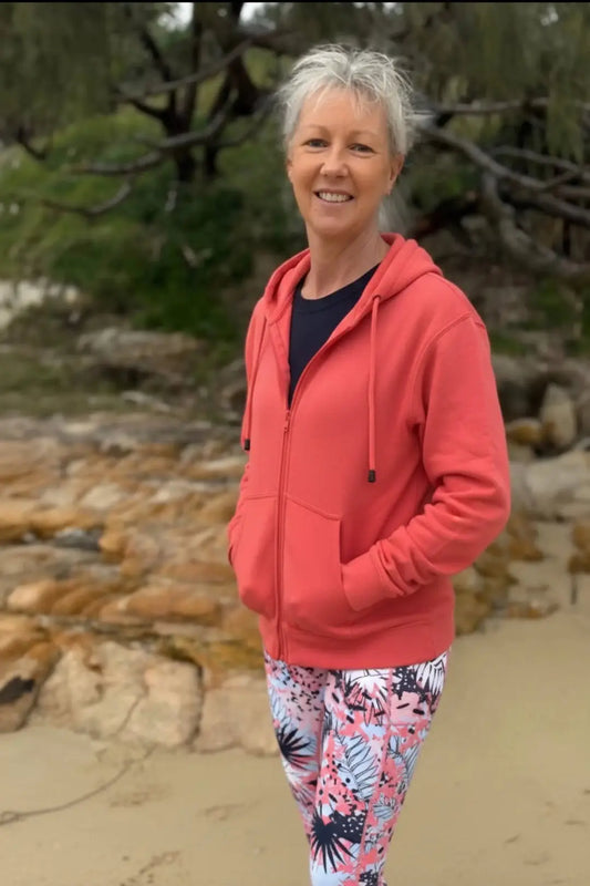 A coral-red fleecy zip hoodie with front pockets and hood worn over a dark blue top featuring fleecy zip hoodies design