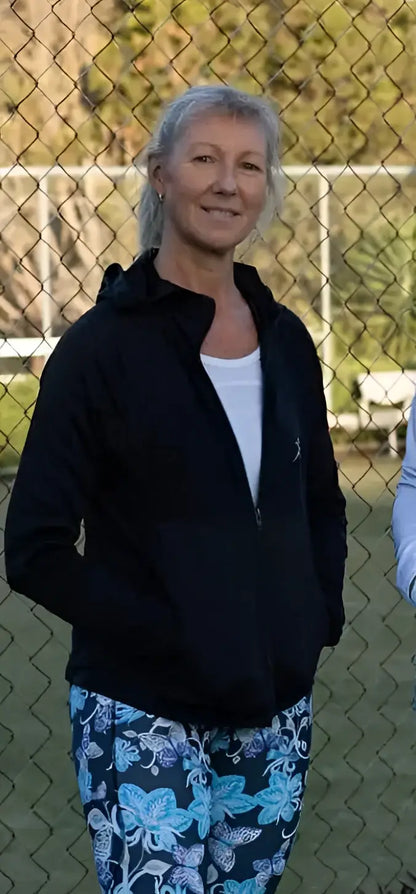A woman wearing a black fleecy zip hoodie over a white top paired with blue floral zip hoodies pants