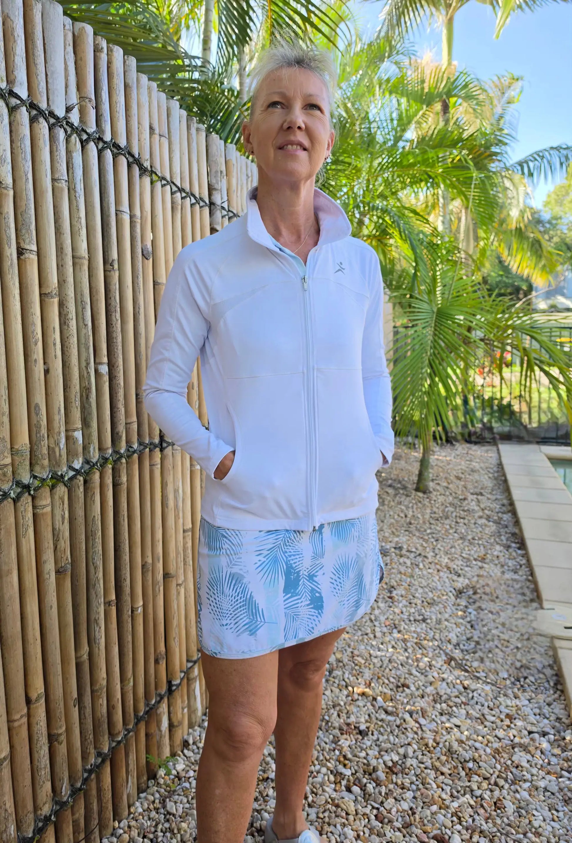 White zip-up athletic jacket with light blue palm leaf pattern paired with matching shorts for sportswear use