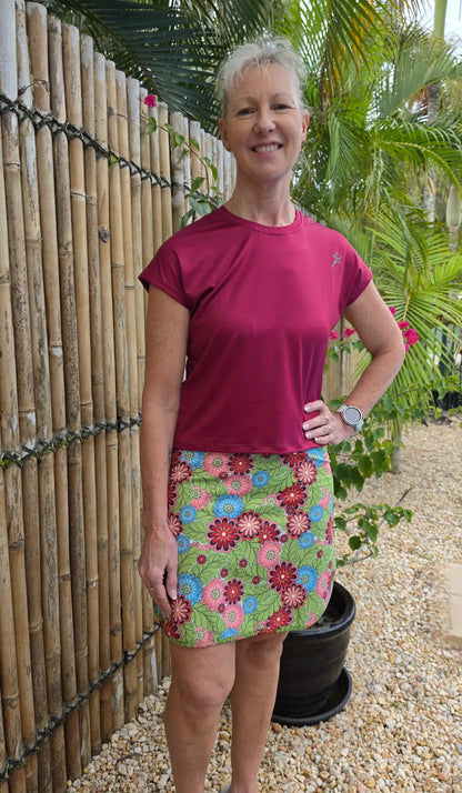 A holli mesh tee paired with a vibrant floral-patterned mini skirt in green pink and blue highlighting playful length
