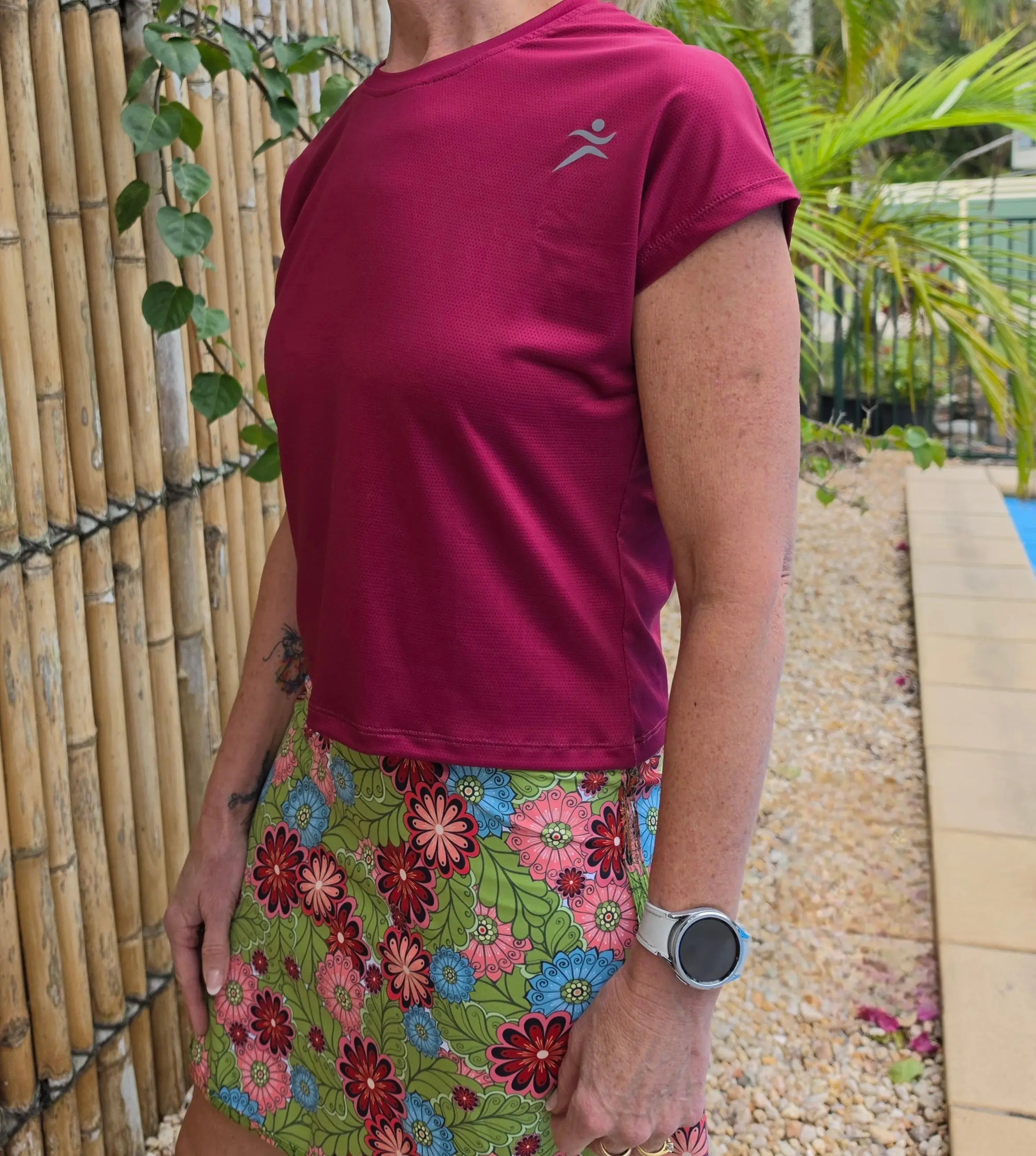A vibrant magenta holli tee with a subtle gray logo and breathable mesh fabric designed for active wear length