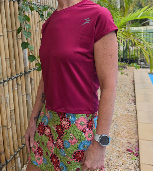 A vibrant magenta holli tee with a subtle gray logo and breathable mesh fabric designed for active wear length
