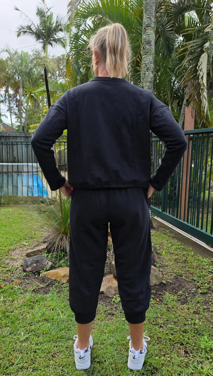 Black kozy fleecy top with pockets, cropped long sleeves, elastic cuffs, cotton polyester activewear jacket