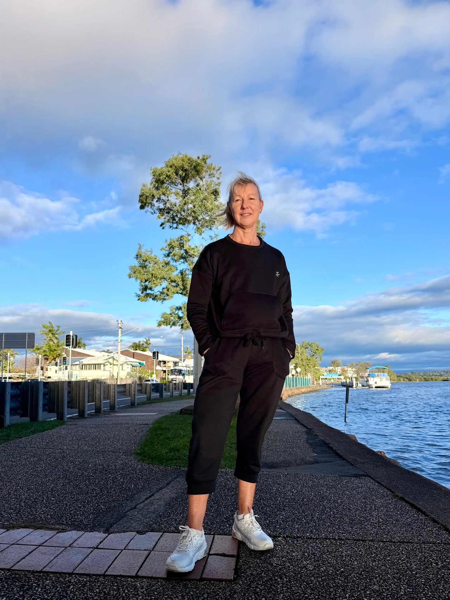 Black kozy fleecy activewear sweatset with drawstring waistband cotton polyester fabric and subtle chest logo paired with white sneakers