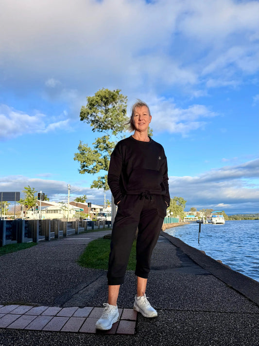 Black kozy fleecy activewear sweatset with drawstring waistband cotton polyester fabric and subtle chest logo paired with white sneakers
