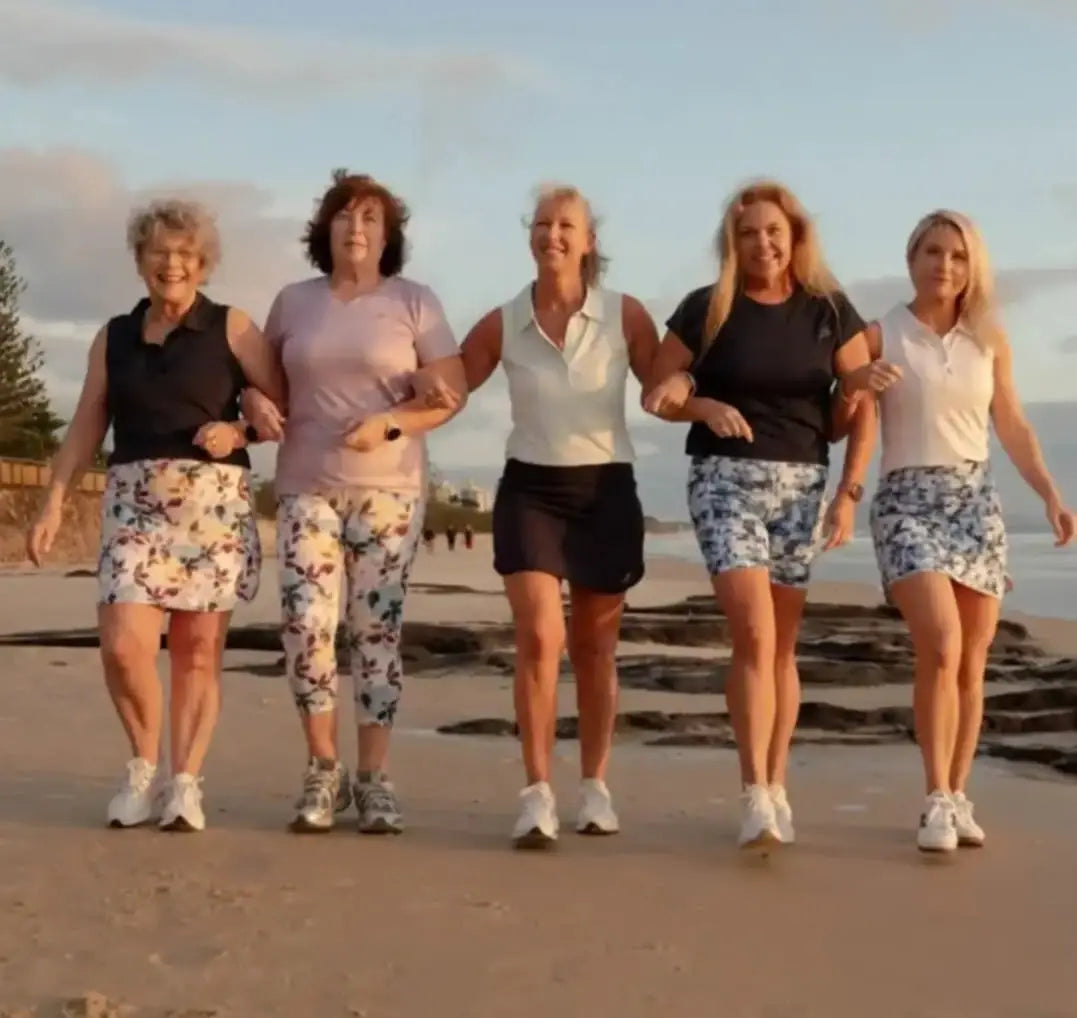 Five women walking on a beach wearing casual summer attire including the laini longer skort with pockets in various sizes