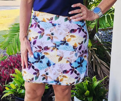 A vibrant patterned laini longer skort with colorful leaf design in purple blue yellow and green on light fabric with pockets