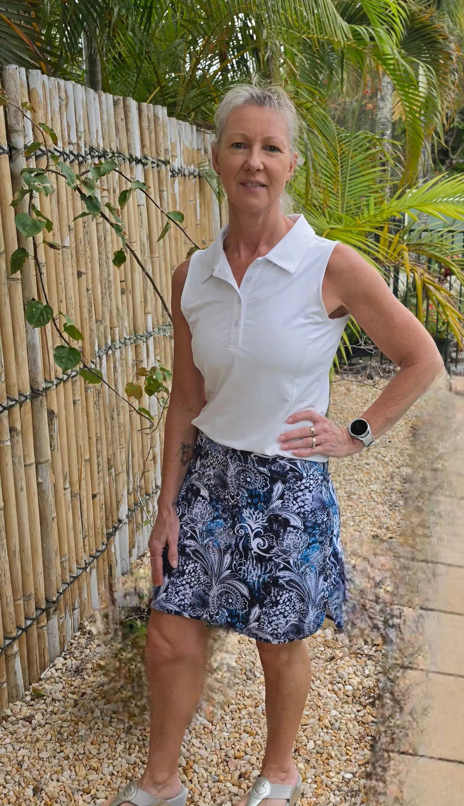 White sleeveless polo shirt with collar paired with longer length lotus skort available in sizes xs to 3xl