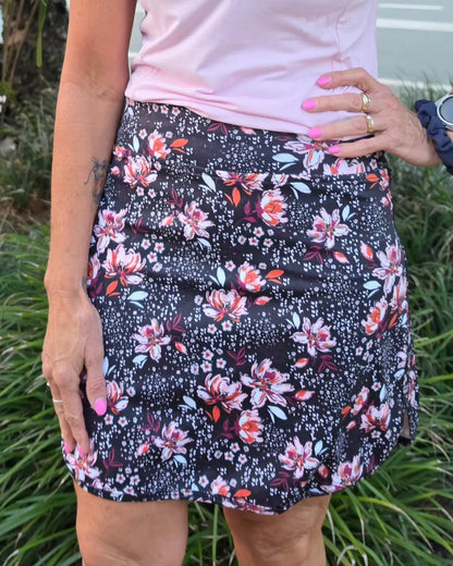 Morgan longer skort with pockets featuring a black floral print mini skirt with pink white and orange blossoms and green leaves