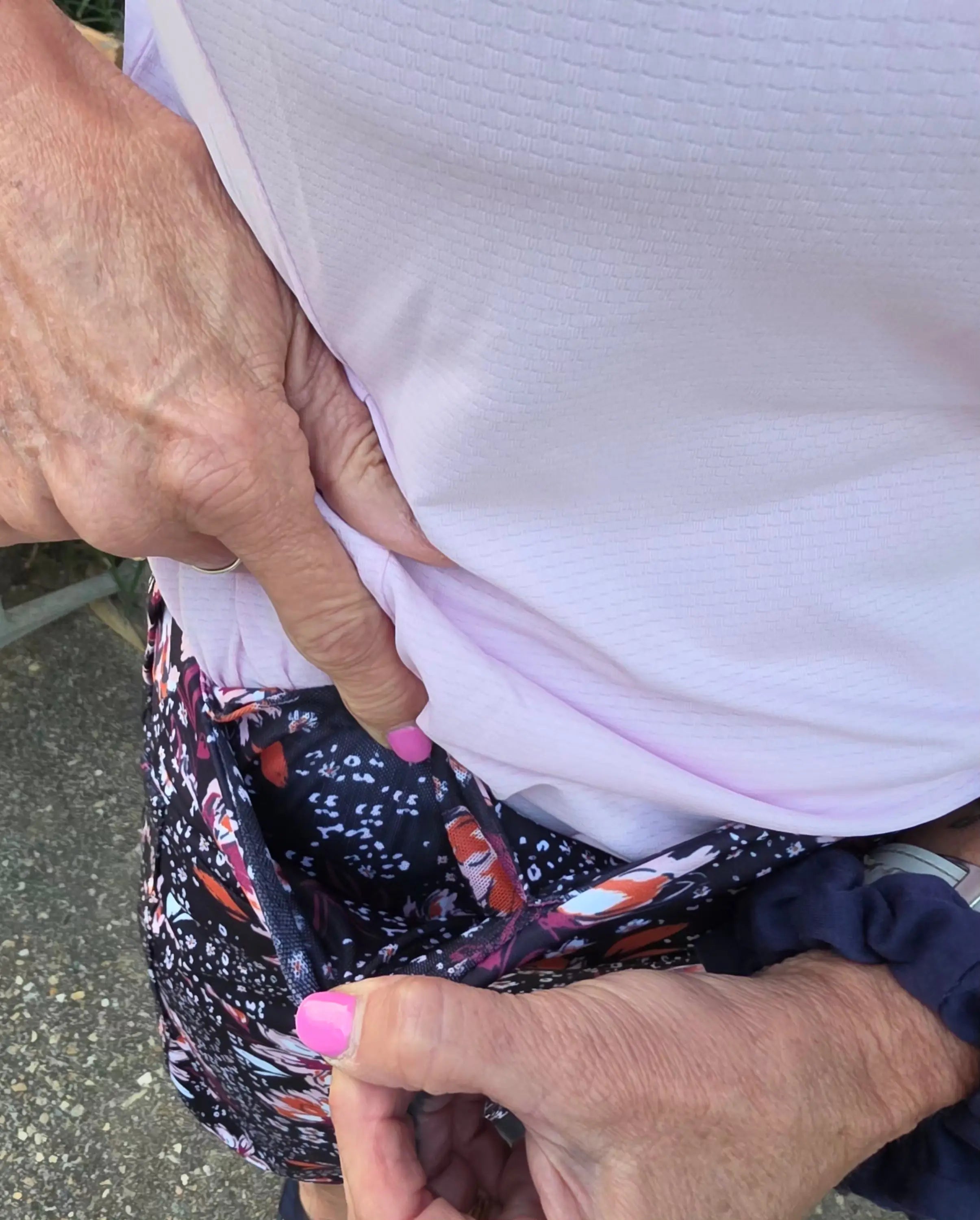 A woman’s hand pulls open the side pocket of a dark blue black and white patterned morgan longer skort with pockets
