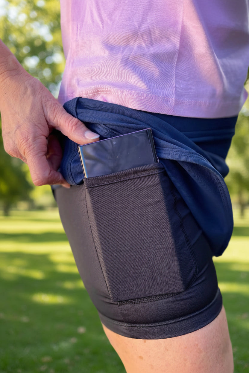 A mid-length Navy skort, perfect for tennis, golf, or pickleball. It features undershorts with convenient pockets