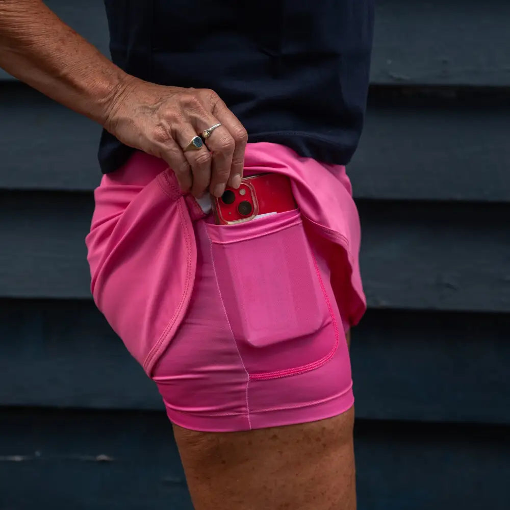 A pink skort features an outer skirt layer and attached undershorts with visible pockets on the thighs.