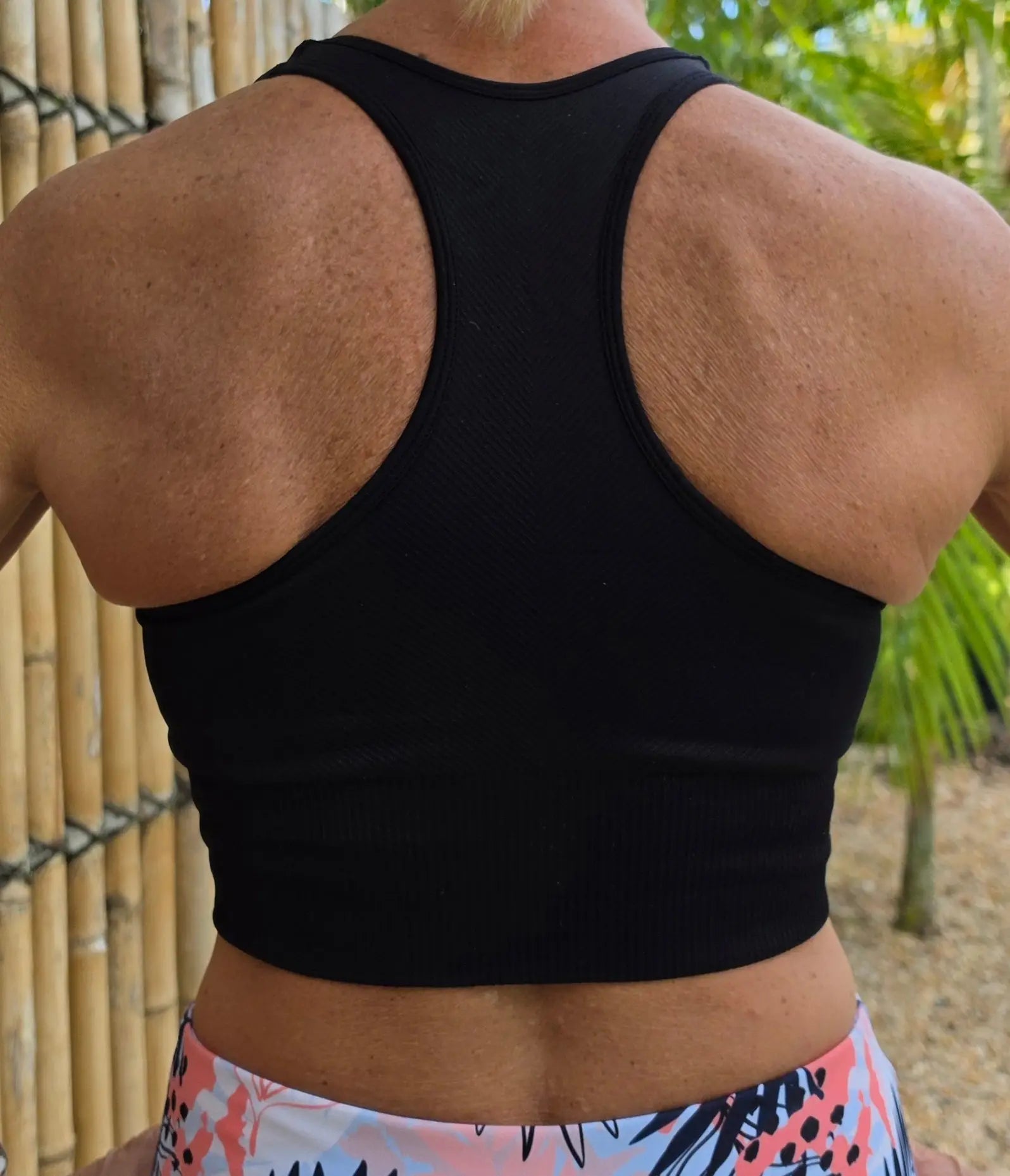 Black racerback sports bra with a snug supportive fit shown from the back as part of the relaxed crop top collection