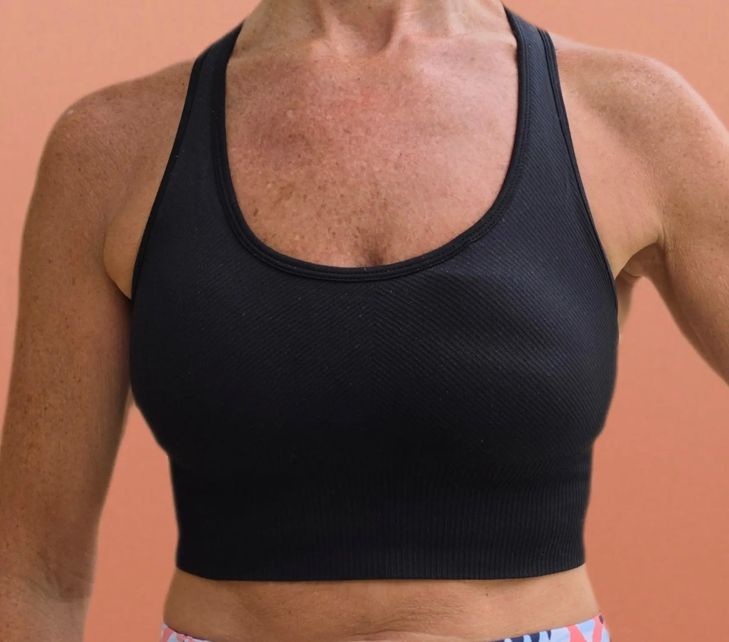 Black ribbed knit sports bra with scoop neckline and cropped hem in relaxed crop top style