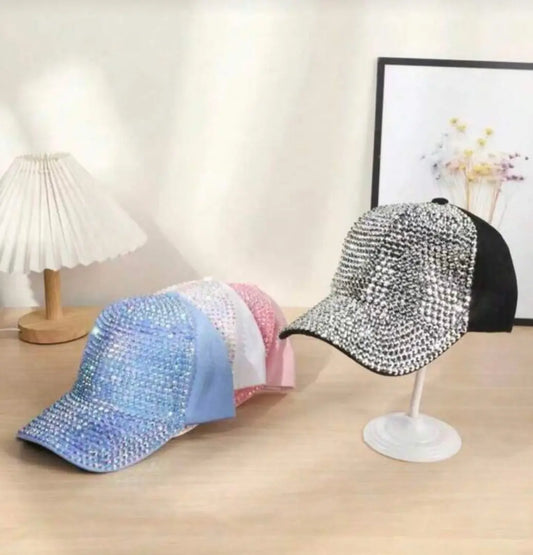 A sparkling silver and black rhinestone baseball cap with iridescent jewels displayed on a white stand