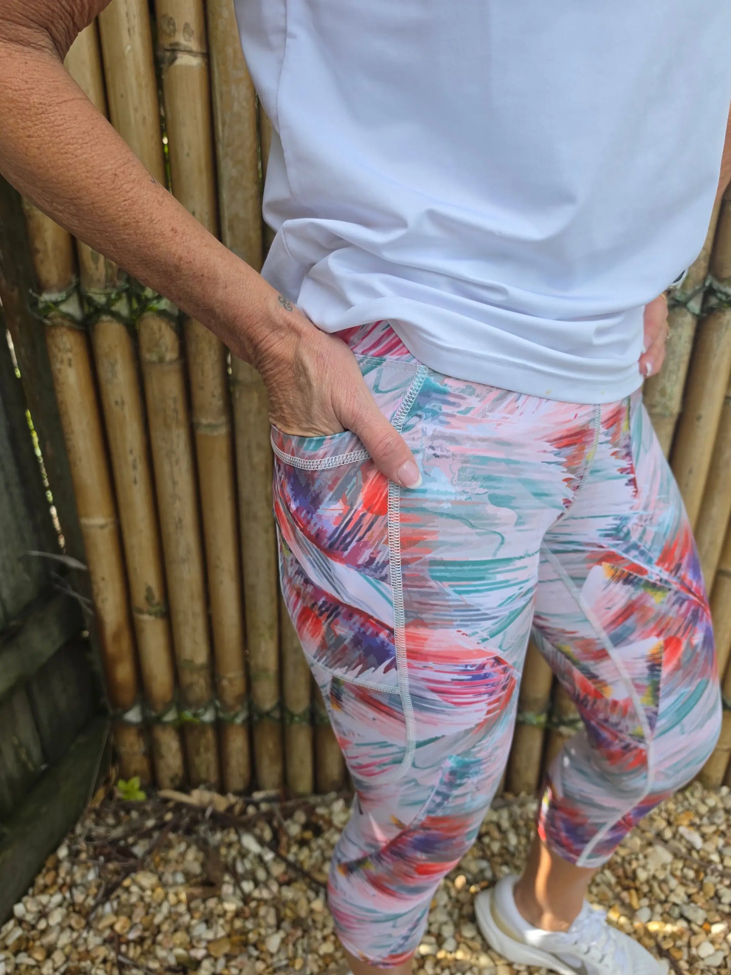 Toni 3/4 active leggings feature colorful moisture wicking paint-splatter capri design in pink teal red and purple hues