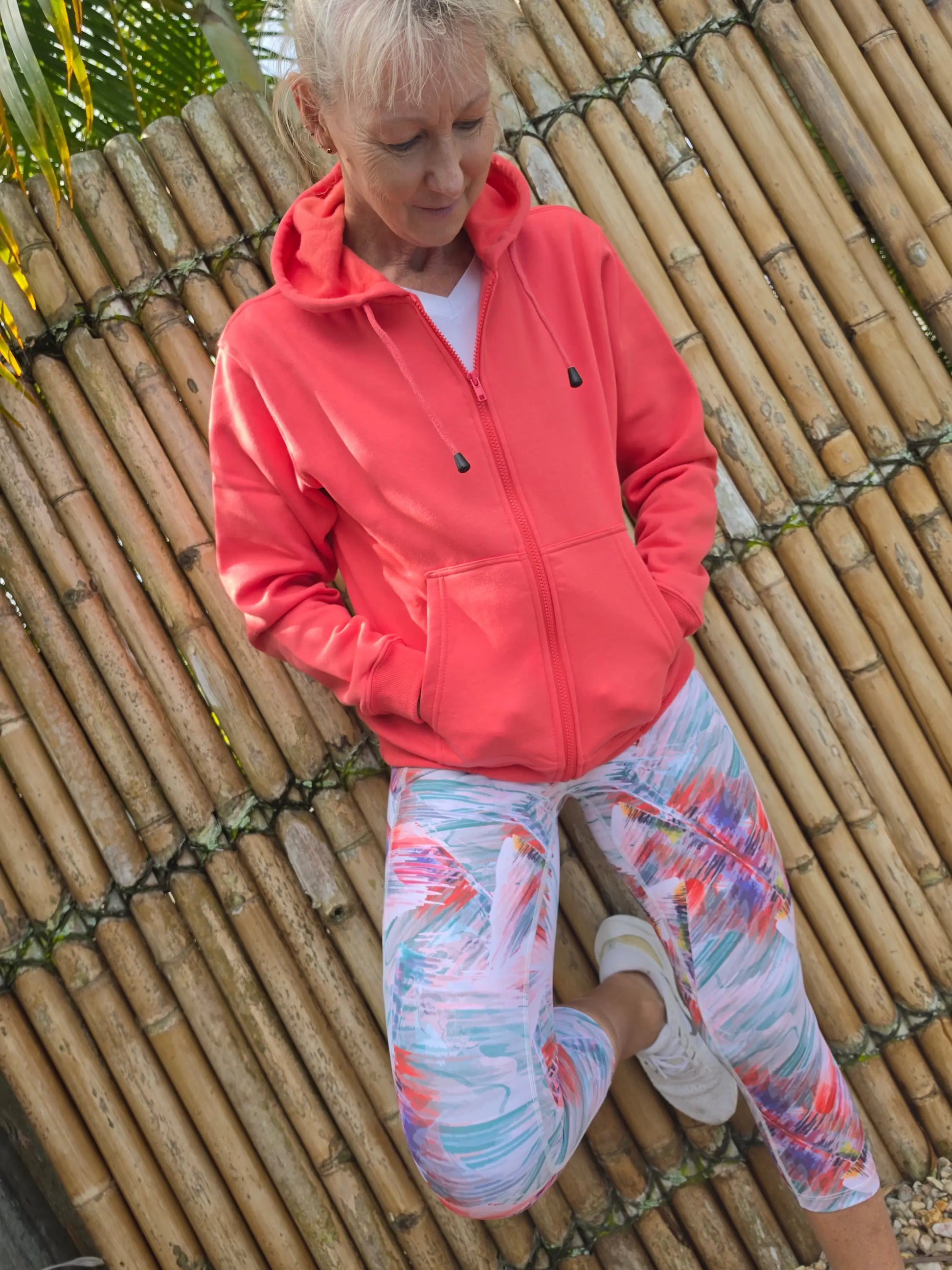 A coral-colored fleece zip-up hoodie with black zipper pulls paired with moisture wicking toni 3/4 active leggings activewear