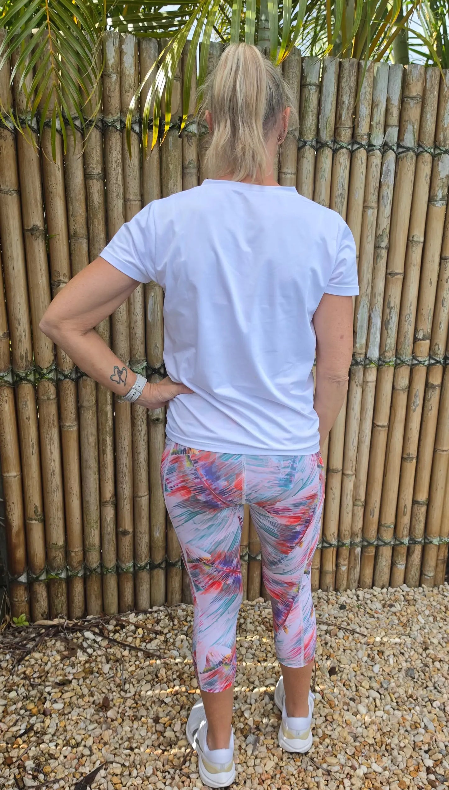 A woman wearing white short-sleeved t-shirt and colorful patterned moisture wicking toni 3/4 active leggings