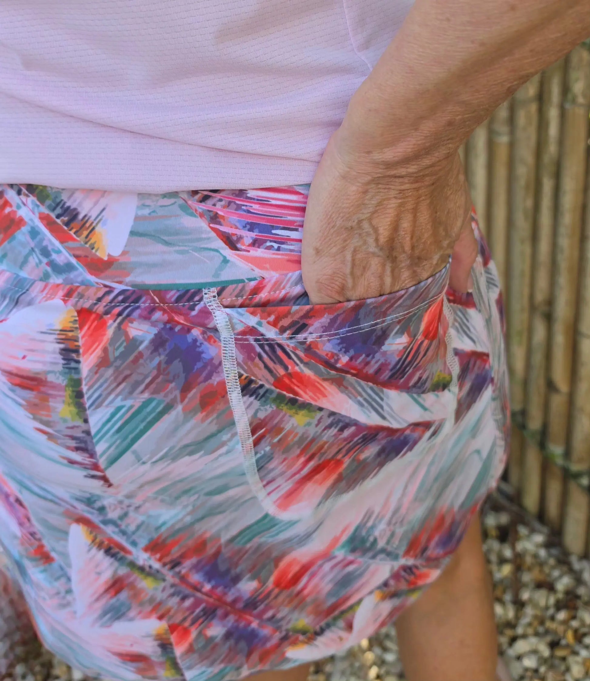 Toni longer length skort with pockets features colorful abstract pattern in red purple and teal on white base for stylish wear