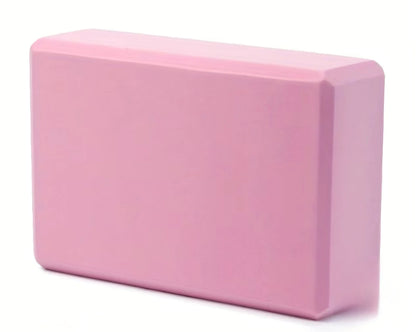 A solid pink foam yoga block with smooth rounded edges and a matte finish for comfortable activewear practice