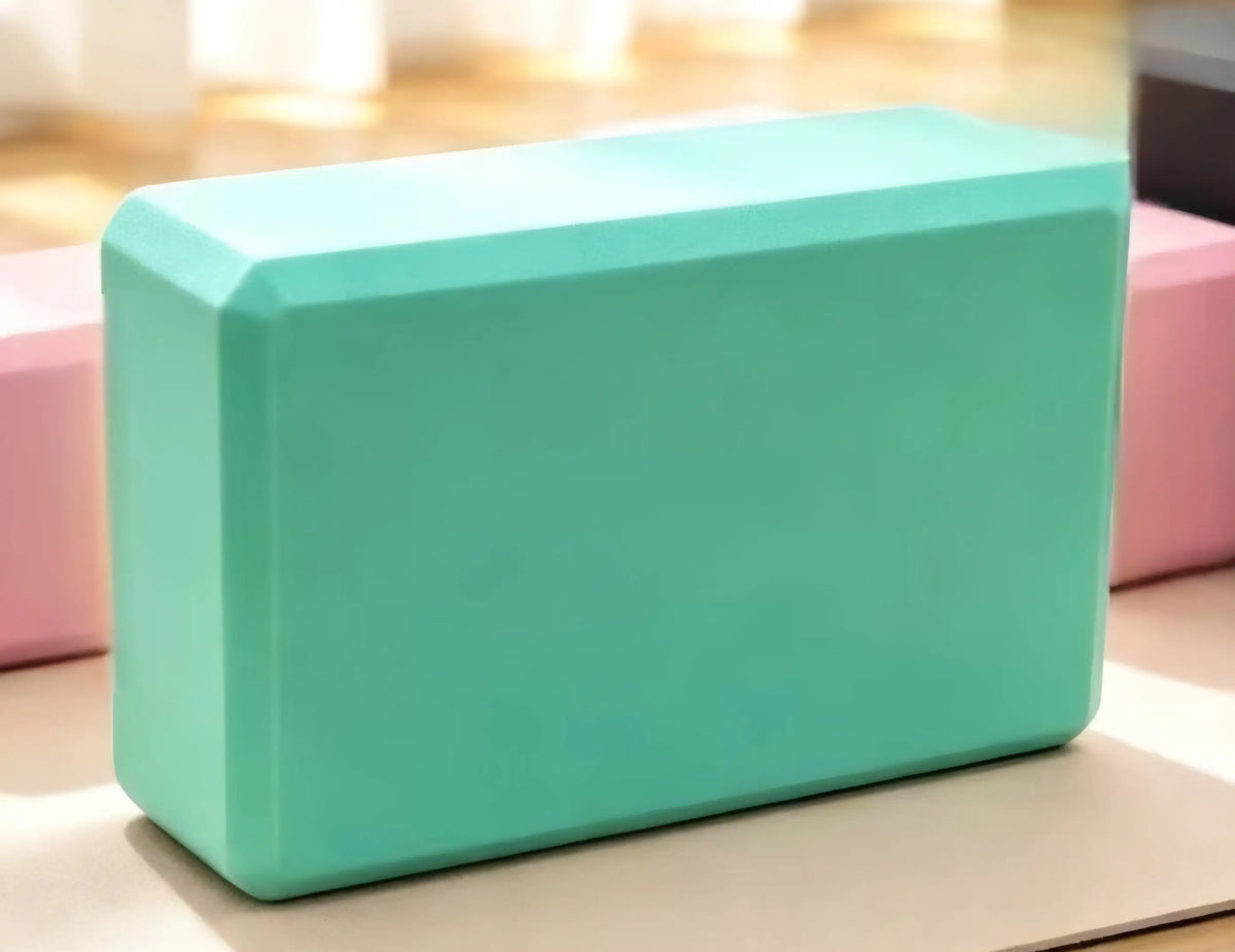 A solid teal foam yoga block with smooth rounded edges and a matte finish for activewear practice